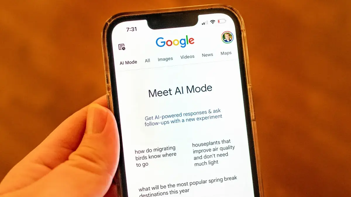 Google AI Mode displayed on a smartphone held against an orange background.